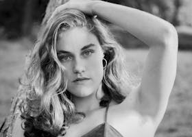 Elegant black and white portrait of a young woman in a natural setting.